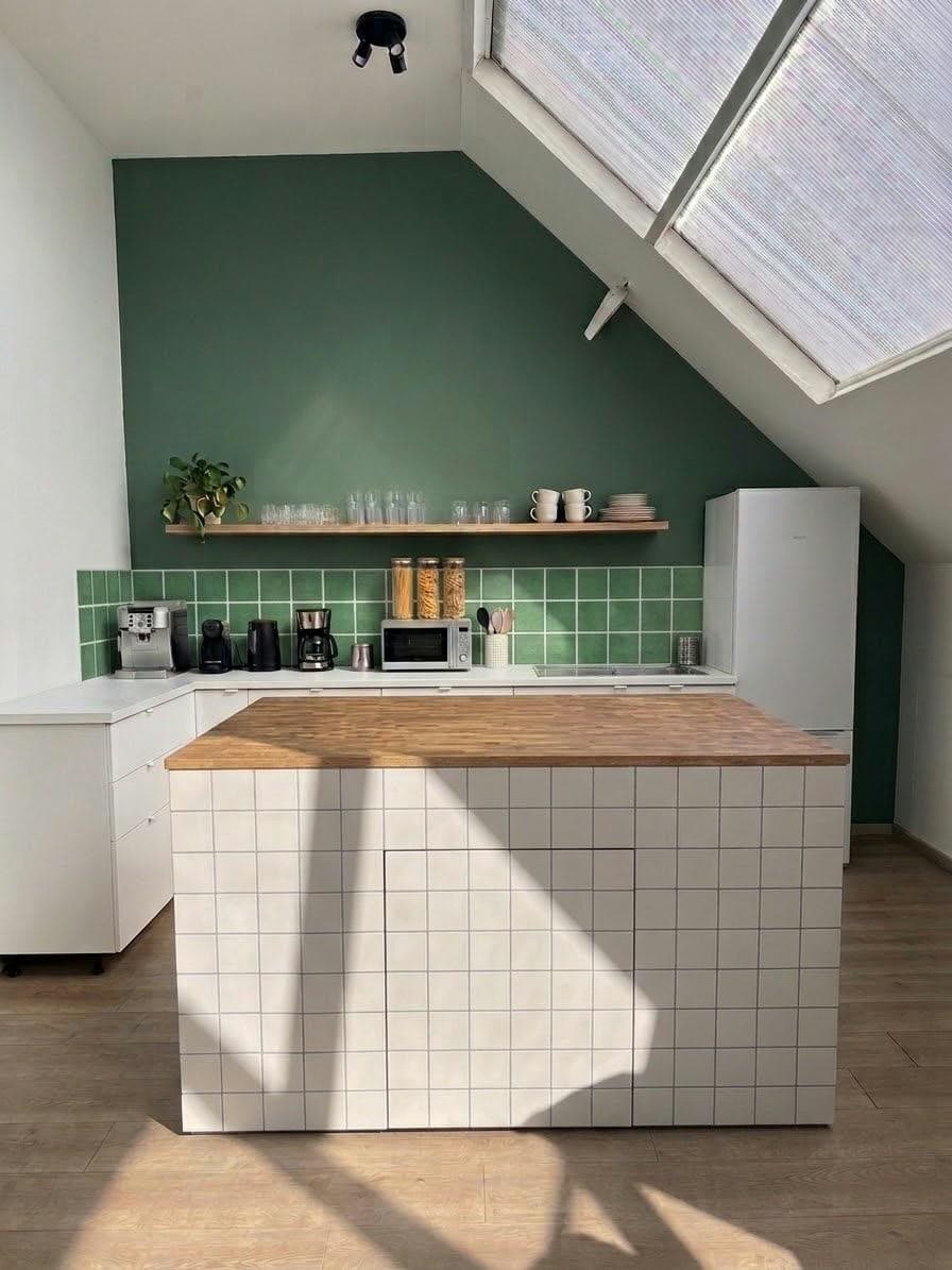 Décor cuisine d'un studio Gust, carrelage vert et plan de travail en bois
